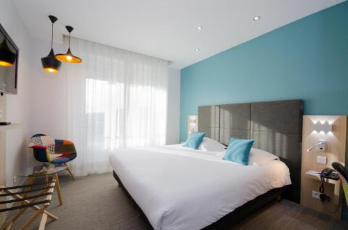 a bedroom with a large white bed and a chair at Best Western Plus Hotel Plaisance in Villefranche-sur-Saône