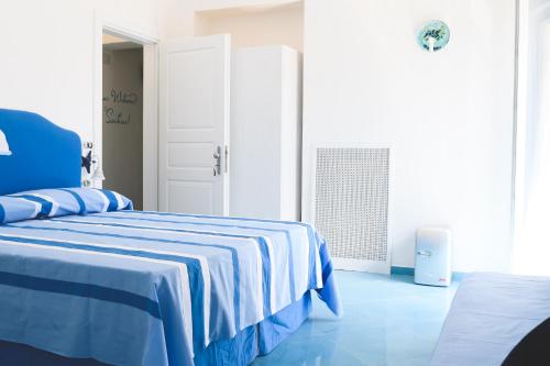 a white room with a bed with a blue blanket at Parco Augusto in Capri