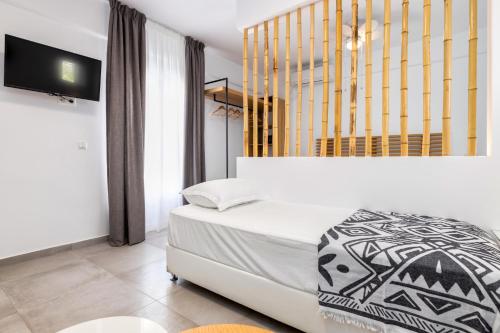 a bedroom with a white bed and a television at Golden Beach Hotel in Chrissi Akti
