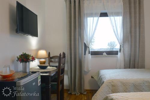 a room with two beds and a table with a television at Willa Fałatówka Mielenko - Mielno Wczasy nad morzem in Mielenko
