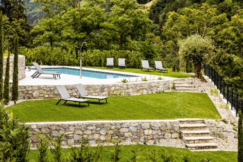 a backyard with a swimming pool and a stone wall at Panorama Residence Saltauserhof Resort in Saltusio