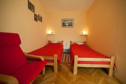 een kamer met 2 rode bedden en een rode stoel bij 10 minutes walk to the lakes in Plitvička Jezera