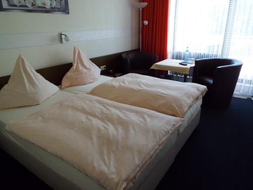 Bett mit weißer Bettwäsche und Kissen in einem Zimmer in der Unterkunft Park-Hotel in Bad Hönningen
