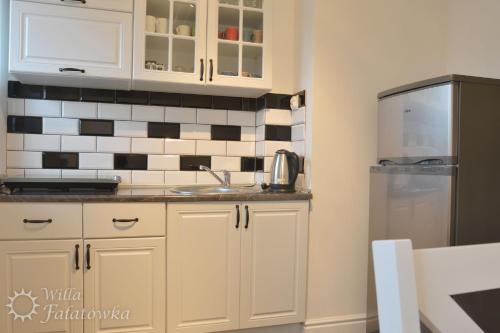 a kitchen with white cabinets and a stainless steel refrigerator at Willa Fałatówka Mielenko - Mielno Wczasy nad morzem in Mielenko