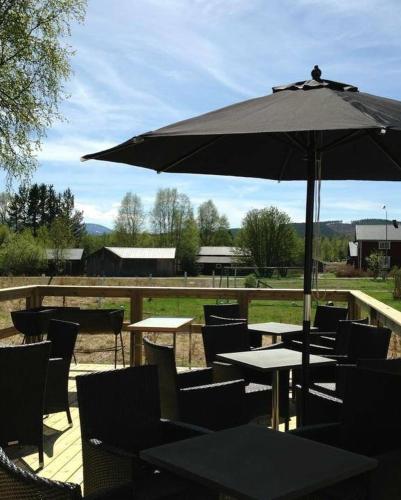 a patio with tables and chairs and an umbrella at Sonfjällsgårdens Wärdshus & Hotell in Hede