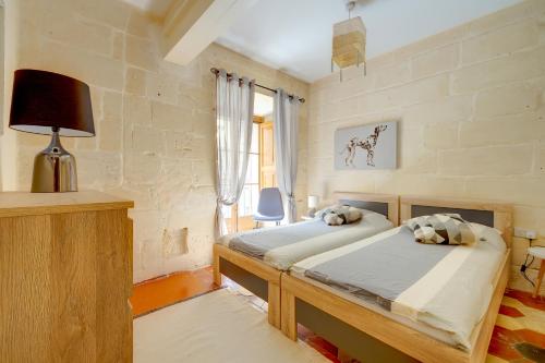 バレッタにあるCentral and Cosy 2BR Apartment in Vallettaのベッドルーム1室(ベッド2台、ランプ、窓付)