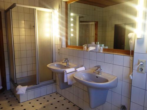 a bathroom with two sinks and a mirror at Tepe's Gasthof in Schwarmstedt