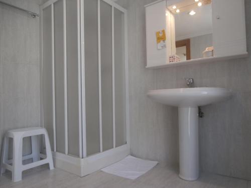 ein Badezimmer mit einem Waschbecken, einem Spiegel und einem Stuhl in der Unterkunft Hostal El Volante in Estella
