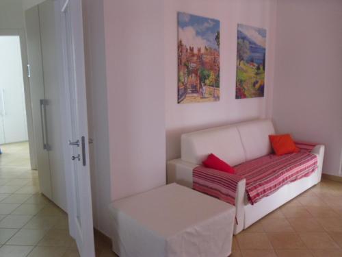 Sofá blanco con 2 almohadas rojas en una habitación en Appartamento Villa Tony, en Lazise