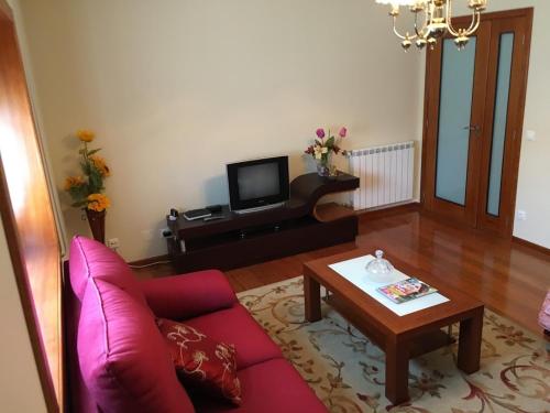 a living room with a red couch and a coffee table at Casa do Reguengo in Arouca