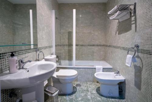 a bathroom with a sink and a toilet and a tub at Casa Montesol in Cáceres