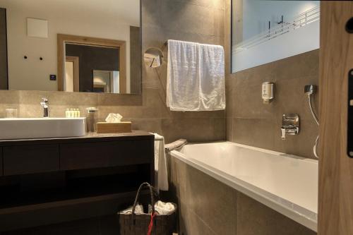 bagno con vasca, lavandino e specchio di Hotel Gnollhof a Chiusa