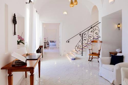 sala de estar blanca con mesa y escalera en La Bizantina Luxury Villa, en Positano