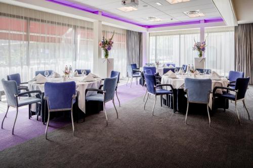 uma sala de banquetes com mesas e cadeiras e iluminação roxa em Holiday Inn Eindhoven Centre, an IHG Hotel em Eindhoven