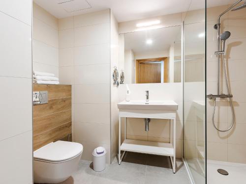 La salle de bains est pourvue de toilettes, d'un lavabo et d'une douche. dans l'établissement VacationClub – Seaside Apartament 108, à Kołobrzeg