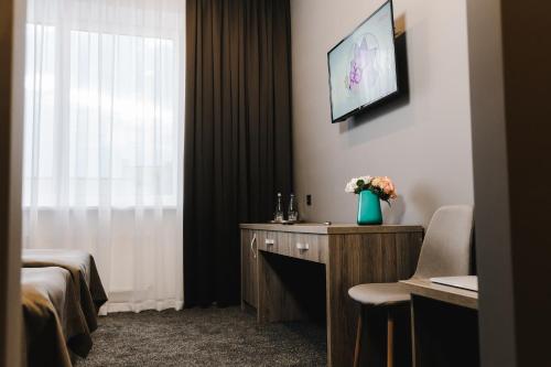 a room with a bed and a table with a vase of flowers at Готельно-рестораний комплекс Silver in Ivano-Frankivsʼk