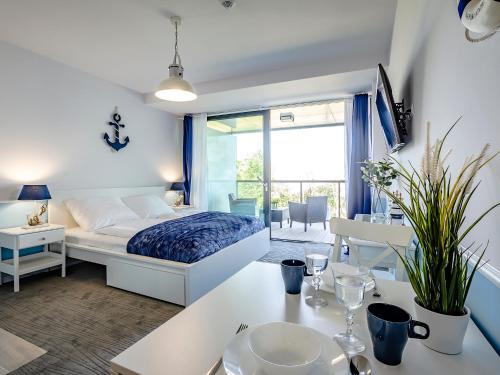 a bedroom with a bed and a table with a dining room at VacationClub - Seaside Apartament 109 in Kołobrzeg