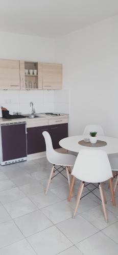 a kitchen with a table and two white chairs at Studio Stela 3 in Povljana