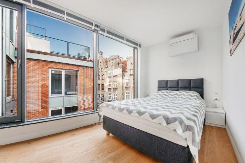 - une chambre avec un lit et une grande fenêtre dans l'établissement VIU Apartament z tarasem w sercu Gdańska, à Gdańsk