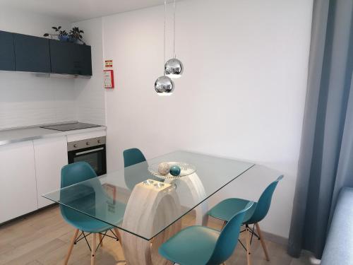 a glass table with blue chairs in a kitchen at PÉROLA d'ÓBIDOS T3 in Gaieiras