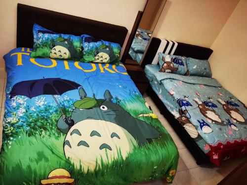 ein Schlafzimmer mit 2 Betten und einem Kuhgemälde in der Unterkunft 12 pax Bidor Totoro House in Bidur