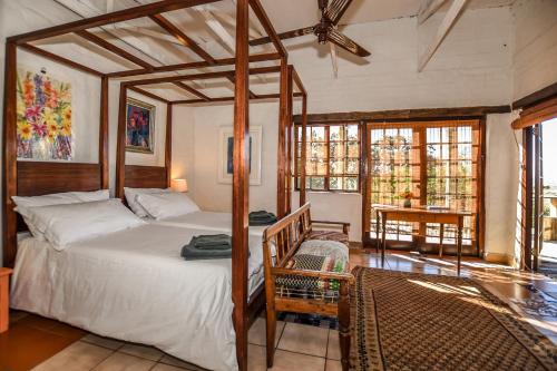 a bedroom with a canopy bed and a table at Eloff Guest House and Gallery in White River