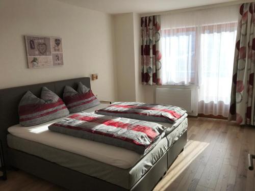 a bedroom with two beds and a window with curtains at Haus Marjanne in Niederau