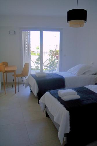 une chambre avec deux lits et une table et une fenêtre dans l'établissement Arbre Blanc, une folie montpelliéraine, à Montpellier