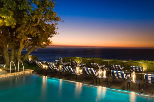 una piscina con sillas y luces frente al océano en Twelve Apostles Hotel & Spa, en Ciudad del Cabo