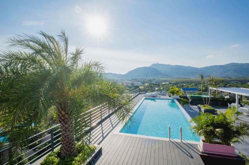 een zwembad met een palmboom op een balkon bij NOON Village Tower 1 in Chalong 