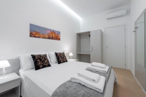 a white bedroom with a white bed with towels on it at Milan Royal Suites - Centro in Milan