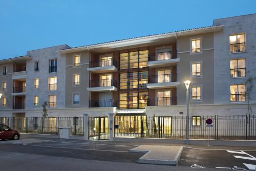an apartment building with a parking lot in front of it at Domitys Les Cigales du Lubéron in Cavaillon
