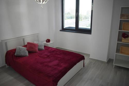 a bedroom with a bed with a red blanket at Apartment By The Lake with a View in Mamaia