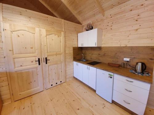 a kitchen with white cabinets and a wooden wall at ATJ Bursztynowy Zakątek in Kąty Rybackie