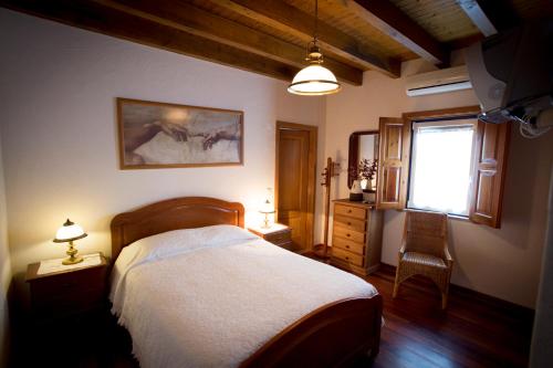 1 dormitorio con cama, ventana y silla en A Palhota, en Alpalhão