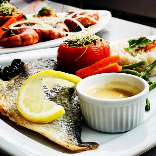 a plate of fish with a lemon slice and vegetables at Le Cheval Blanc in Jargeau