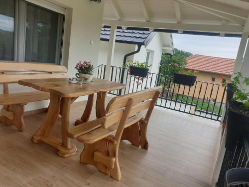 a wooden table and benches on a patio with a balcony at Apartmani Kruna in Vrdnik