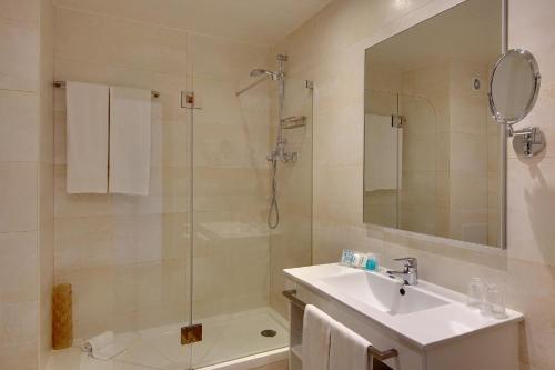 uma casa de banho com um chuveiro, um lavatório e um chuveiro em Hotel Alba em Monte Gordo