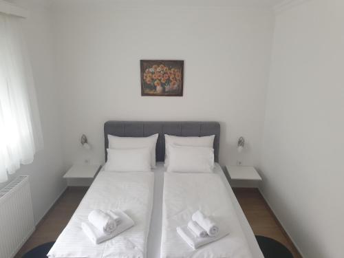 a bedroom with a bed with white sheets and pillows at Apartmani Kruna in Vrdnik