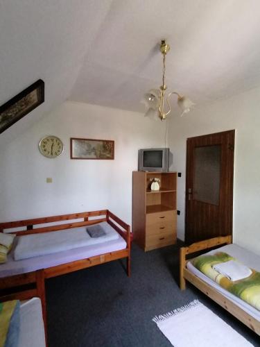 a bedroom with two beds and a clock on the wall at Malomtavi Vendégház in Tapolca