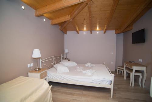 a bedroom with a white bed and a table and a television at Studios Artemis in Lefkada Town