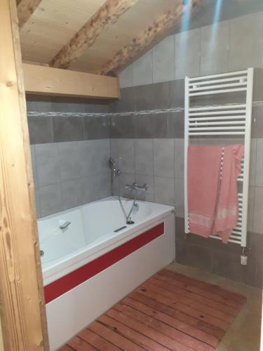 chalet le plan du rtia في مورزين: حمام مع حوض استحمام أبيض ومنشفة وردية