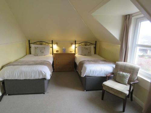 a attic bedroom with two beds and a chair at Duirinish Guest House in Portree