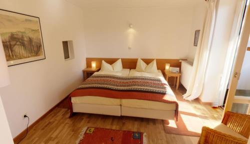 a bedroom with a bed and two tables and two windows at Outdoorhotel Jäger Von Fall in Lenggries