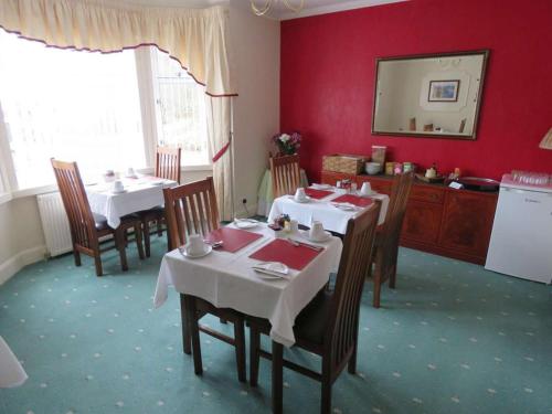 a dining room with tables and chairs and a mirror at Duirinish Guest House in Portree
