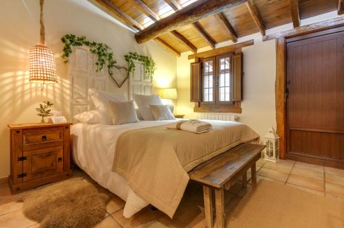 Casa Rural A Cashiña da Lagarteira في فالفيردي ديل فريسنو: غرفة نوم بسرير كبير ومقعد خشبي