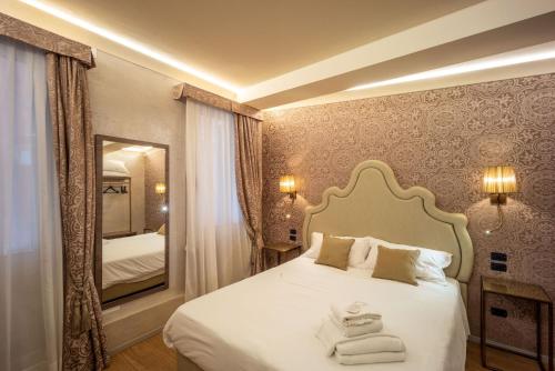 een slaapkamer met een wit bed en een spiegel bij Locanda Cavanella in Venetië