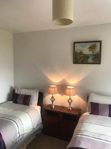 two beds in a room with two lamps on tables at Marguerite's B&B in Glenties