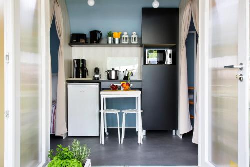 a small kitchen with a white refrigerator and a table at Camping Del Sole Village in Iseo