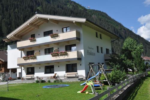 un edificio con un parque infantil delante de él en Gästehaus Holaus en Mayrhofen